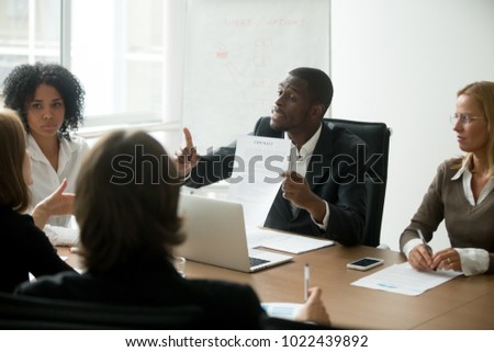 African american businessman disagreeing with contract terms at group multi-ethnic negotiations, black partner arguing about deal conditions or fraud scam pointing at document at multiracial meeting Royalty-Free Stock Photo #1022439892
