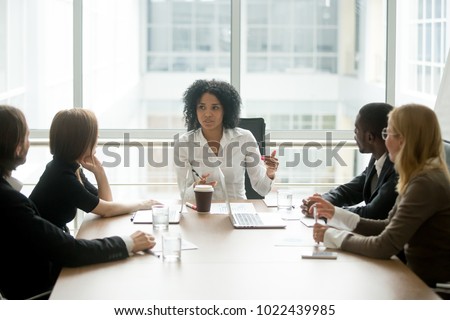 Black female boss leading corporate multiracial team meeting talking to diverse businesspeople, african american woman executive discussing project plan at group multi-ethnic briefing in boardroom Royalty-Free Stock Photo #1022439985