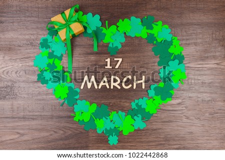 Saint Patrick's Day. Wooden letters "17 march" lying on wooden background in heart shape of green three petal clovers 