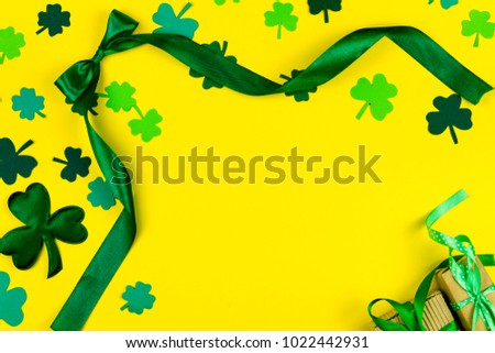 Saint Patrick's Day. Green design curved tape, green three petal clovers and gift's box on yellow background