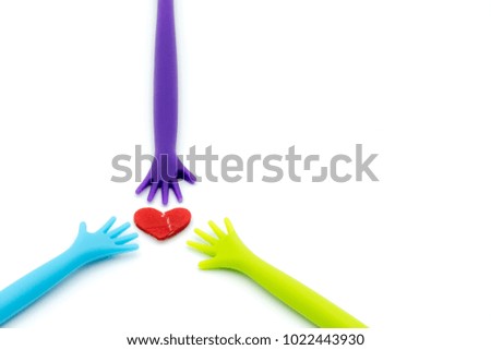 Colorful plastic hands raise up broken heart isolated on white background.