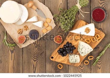 Tasting cheese dish with herbs and fruits on old wooden table. Food for wine party, cheese delicatessen. Menu design.