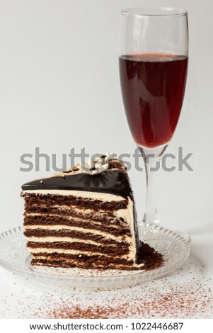 piece of chocolate cake on a glass saucer on a white background decorated with white chocolate and flowers