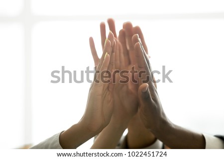 Motivated multiracial business team join hands palms together, black and white diverse people group give high five as concept of successful teamwork and help support unity in common goal achievement Royalty-Free Stock Photo #1022451724
