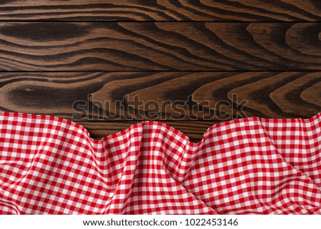 Red checkered tablecloth on an old wooden table. Close up 