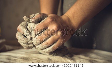 Female potter works with clay, craftsman hands close up, kneads and moistens the clay before work, toned Royalty-Free Stock Photo #1022459941