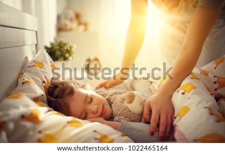 mother wakes up sleeping child daughter girl in the morning Royalty-Free Stock Photo #1022465164