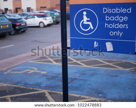 empty car parking spaces for disabled users in UK city car park beside sign for disabled badge holders only
