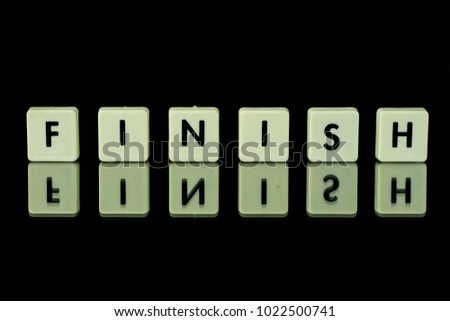blocks with letters set on a glass table. Words arranged from letters on a glass substrate. The words finish. A black background