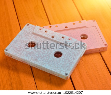 Painted in a pink blue pastel color audio cassette on an orange wooden background. Retro audio technology.Top view.