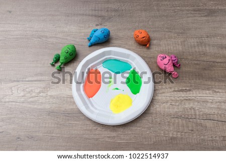 Four paint colors on a plate and some baloons