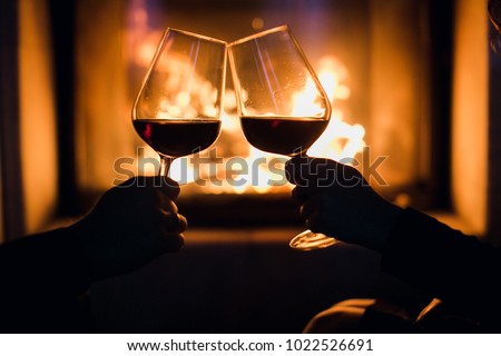Young couple have romantic dinner with wine over fireplace background
