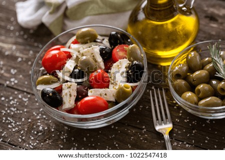 Greek salad with fresh vegetables, feta cheese and green olives on a wooden table background
