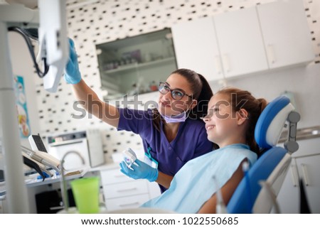 Dentist female shows on x-ray footage to young patient her problem with teeth 
