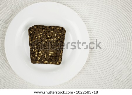 Black bread with seeds on a white plate.