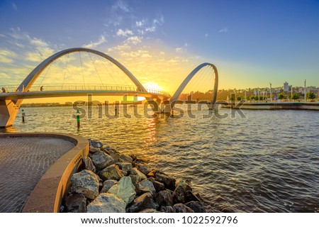 Scenic and iconic Elizabeth Quay Bridge at sunset light on Swan River at entrance of Elizabeth Quay marina. The arched pedestrian bridge is a new tourist attraction in Perth, Western Australia. Royalty-Free Stock Photo #1022592796