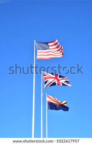 3 flags: USA, UK, Arizona state flag flying on 3 flagpoles