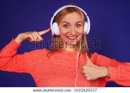 happy blond pointing on headphones and showing thumbs up