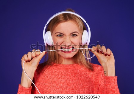 angry blond in headphones biting cord