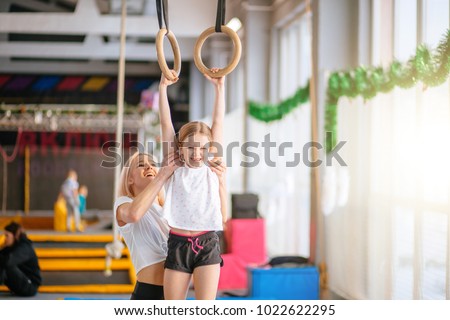 Mother helping her daughter to play sports on gymnastic rings