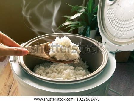 Jasmine rice cooking in electric rice cooker with steam. Soft Focus, Rustic tone picture.