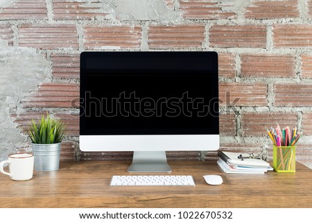 workspace with computer with blank black screen, and office supplies on a wooden desk