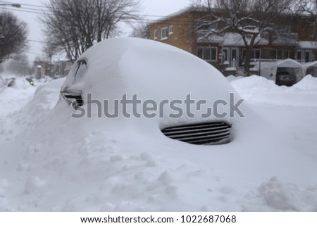 Winter urban scene in Canada. Vehicles covered with snow in the winter blizzard in the parking. Cars in snowdrifts after a snowfall. After the winter storm in Montreal. 