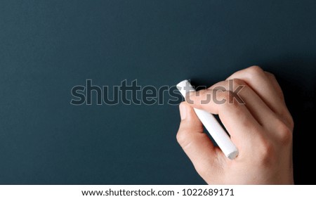 Chalkboard with hand holding white chalk.
