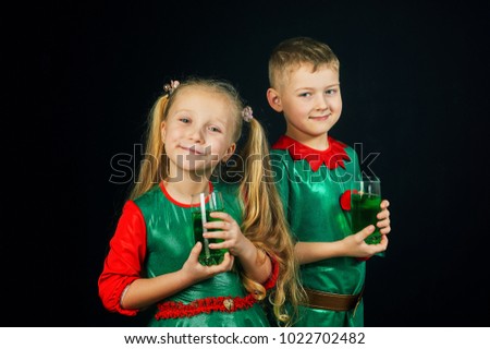 Cheerful children in green suits with a glass of green drink on St. Patrick's day