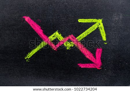 Hand drawing of green and red chalk in up and down arrow shape on black board background