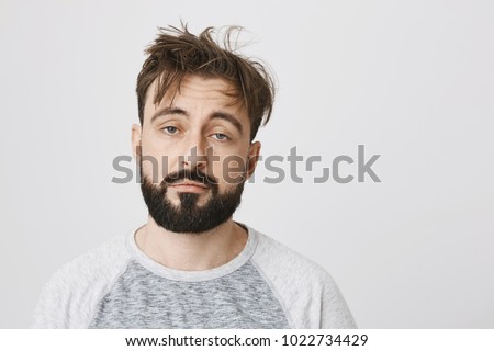 Unsatisfied sleepy guy with messy hair and gloomy smile, standing over gray background. Morning after few drinks can be harsh sometimes. Hangover attacked unexpectedly Royalty-Free Stock Photo #1022734429