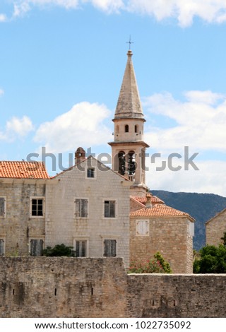 The bell tower of the Church of Saint John and a fragment of the wall of the Old Town of Budva at dawn, Budva, Montenegro 