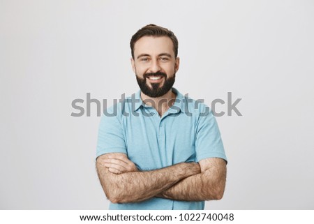 Portrait of a handsome bearded man smiling looking to the camera with his hands crossed isolated on white background. This person looks like an ordinary guy who is sincere and ready to help everyone. Royalty-Free Stock Photo #1022740048