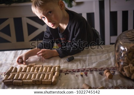 Little boy collects a pattern - a picture of wine corks