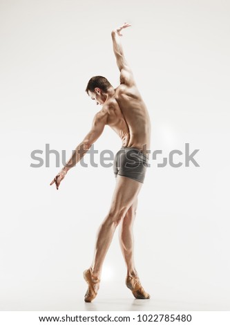 Athletic ballet dancer in a perfect shape performing isolated on the white background. Studio shot. Ballet concept