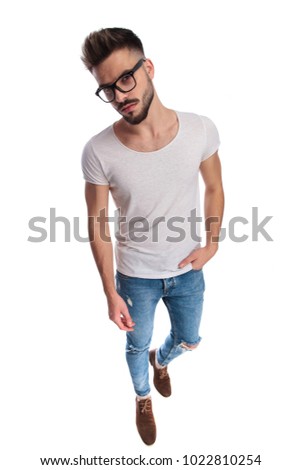full body picture of a young casual man with hand in pocket and wearing eyeglasses on white background