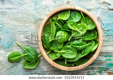 Fresh baby spinach leaves in bowl on wooden background Royalty-Free Stock Photo #1022814211