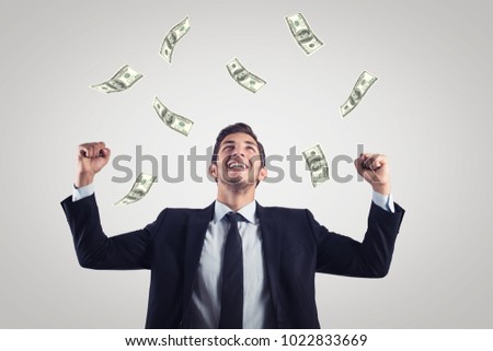 happy excited businessman raising hands up and looking up under money rain.