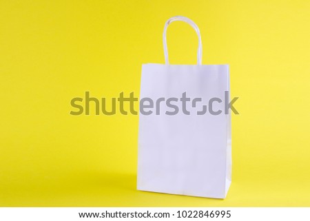 white shopping bag on yellow background with space for your logo or text