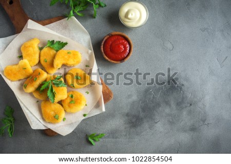Chicken nuggets and sauce on grey concrete background, copy space. Fried  chicken brest nuggets with ketchup and mayonnaise.