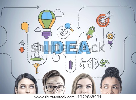 Heads of a diverse business team members. They are brainstorming standing near a gray wall with a bright idea sketch drawn on it