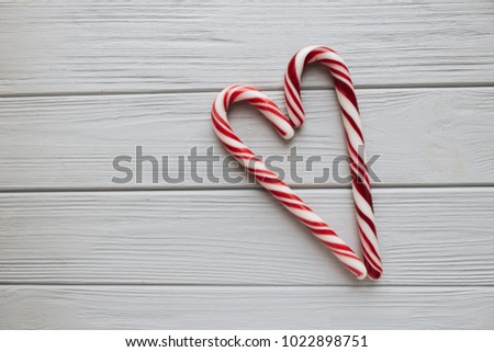 Christmas candy canes in heart shape on wooden background