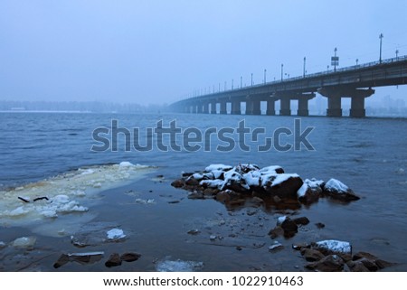 Kyiv winter cityscape with Paton bridge over Dnieper river. Foggy morning view. A few minutes before the snowfall.