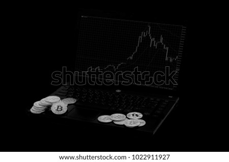 Bitcoin silver and gold layered on a black notebook. Graph display screen. black and white background image.On a black background. 
