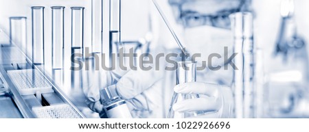 Researcher with pipette and glass flask and many other laboratory utensils Royalty-Free Stock Photo #1022926696