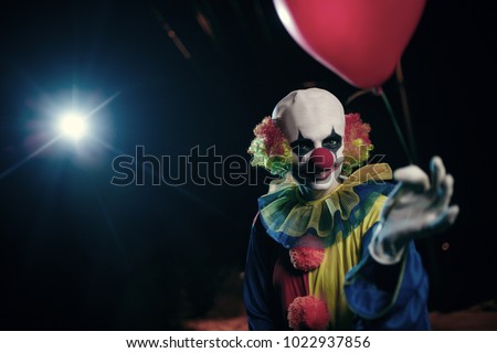 Image of clown with red balloon on background of burning lantern