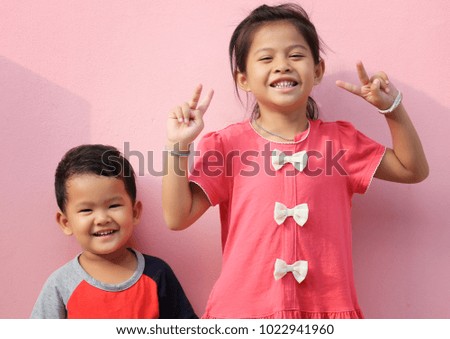 Asian boys and girls in smiling on pink wall background for design concept of happiness.