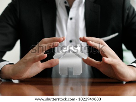Businessman protecting house with hands