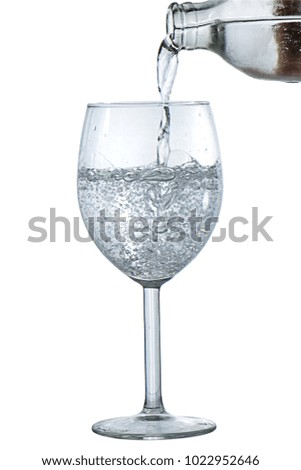 Pouring water from bottle on glass isolated on white background in full depth of field with clipping path.