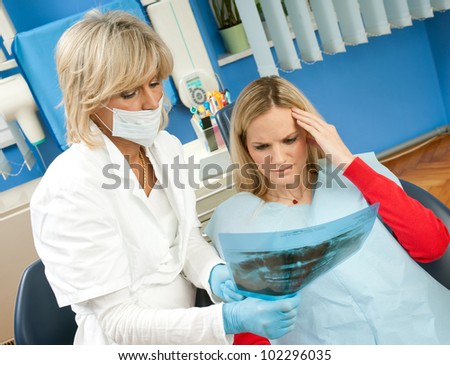 woman dentist and her female patient looking at x-ray image and thinking
